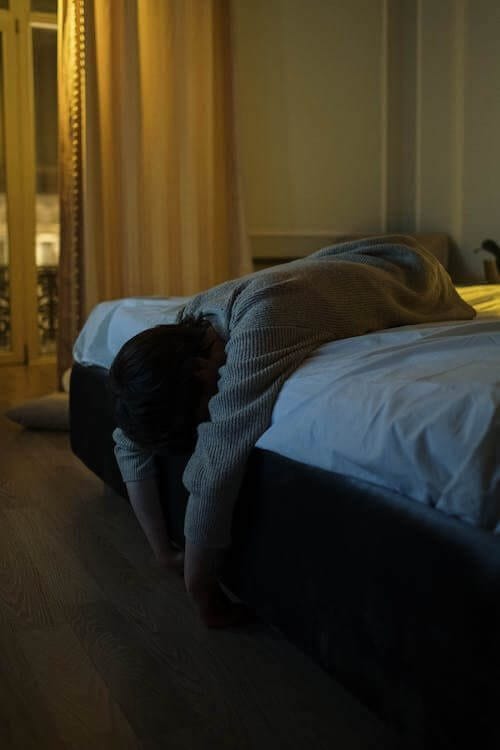 person laying exhausted on their bed. Many factors can contribute to and significantly impact sleep-wake cycle disruption